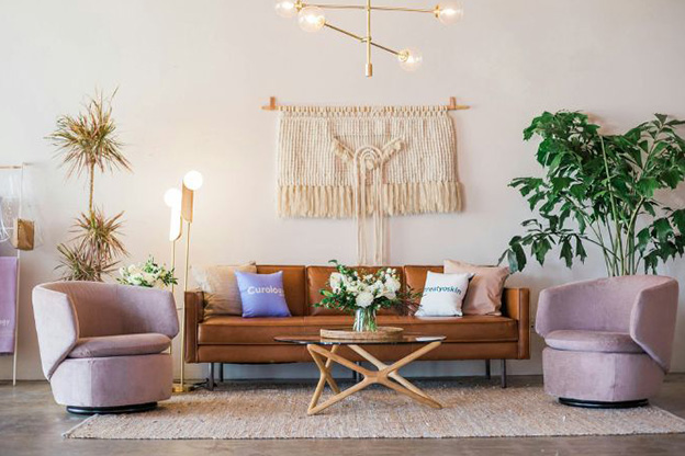 Living room with a leather couch, white side chairs, and a tapestry on the wall.